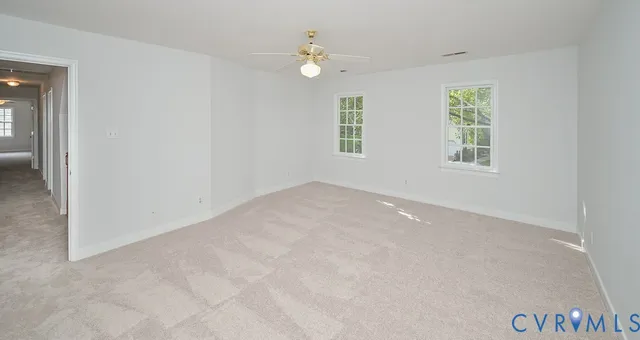 an empty room with windows and ceiling fan