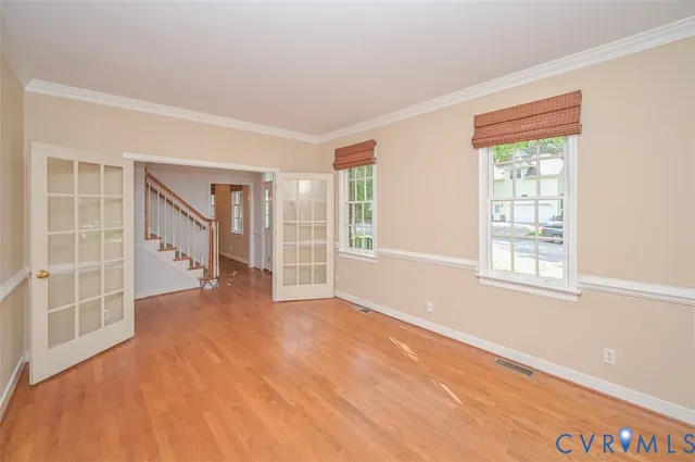 a view of an empty room with a window and wooden floor
