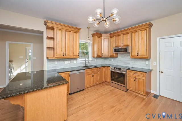 a kitchen with stainless steel appliances granite countertop a sink cabinets and wooden floor
