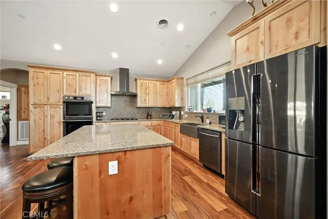 a kitchen with stainless steel appliances a refrigerator a stove a sink and chairs with wooden floor