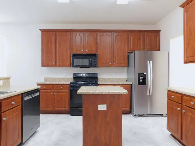 a kitchen with granite countertop wooden cabinets and a stove top oven