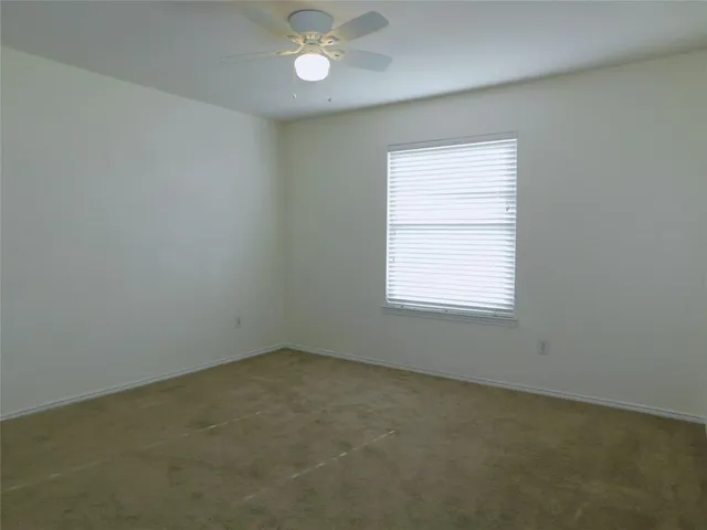 an empty room with a window and a fan