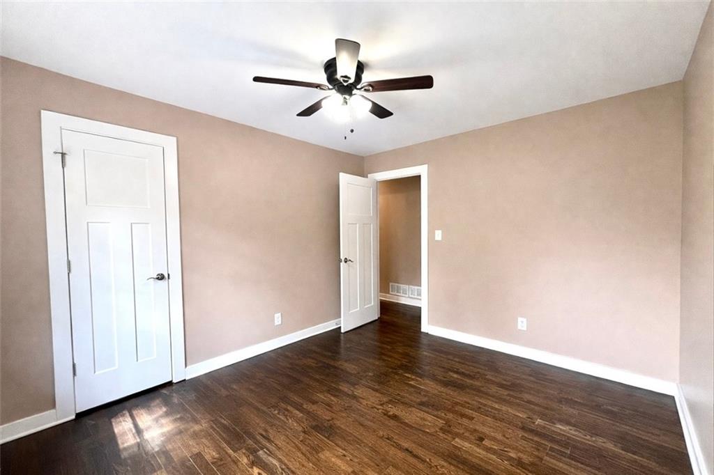 1291 Lorenzo Drive Southwest Atlanta, GA 30310 - Photo 18 of 20 an empty room with wooden floor ceiling fan and windows