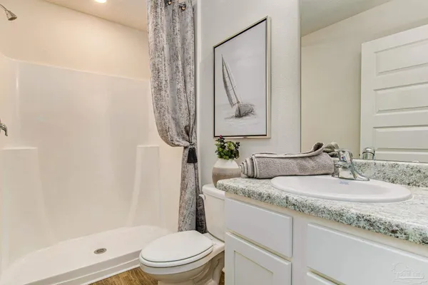 a bathroom with a granite countertop sink a toilet and shower