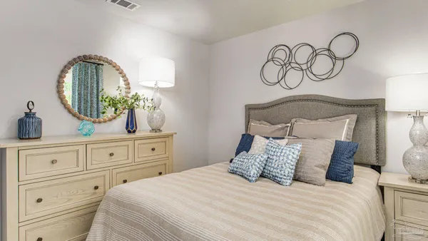 a bedroom with a bed and a mirror on the dresser