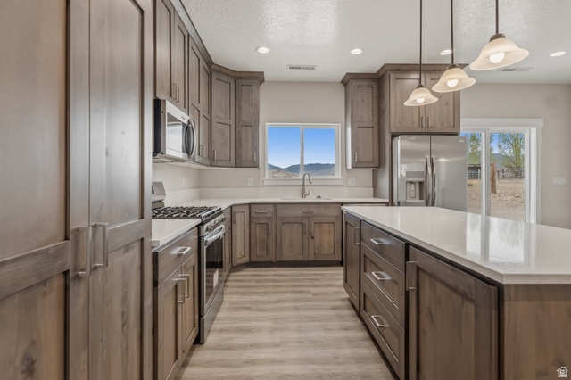 169 West 100 South Joseph, UT 84739 - Photo 10 of 35 Kitchen featuring stainless steel appliances, hanging light fixtures, a kitchen island, light wood finished floors, and light stone counters