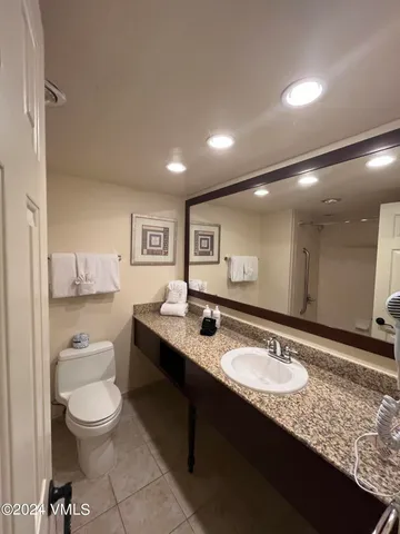 a bathroom with a granite countertop sink a toilet a large mirror and shower