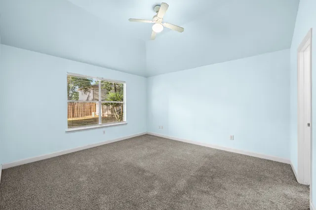 an empty room with a window and ceiling fan