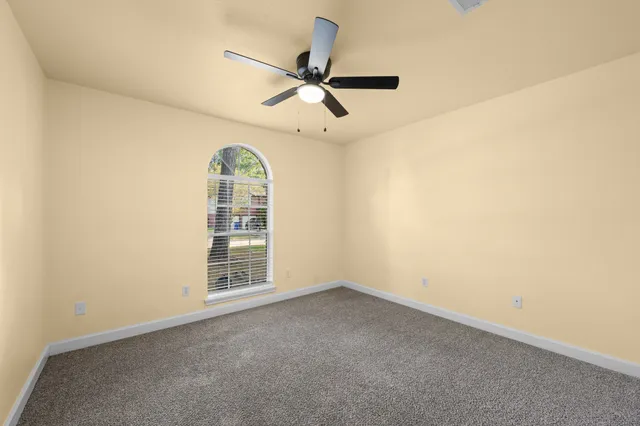 an empty room with a ceiling fan and window