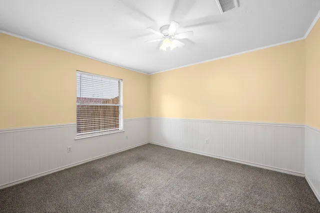 an empty room with windows and chandelier fan