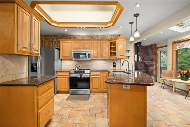 a kitchen with stainless steel appliances granite countertop a sink a stove and a wooden cabinets