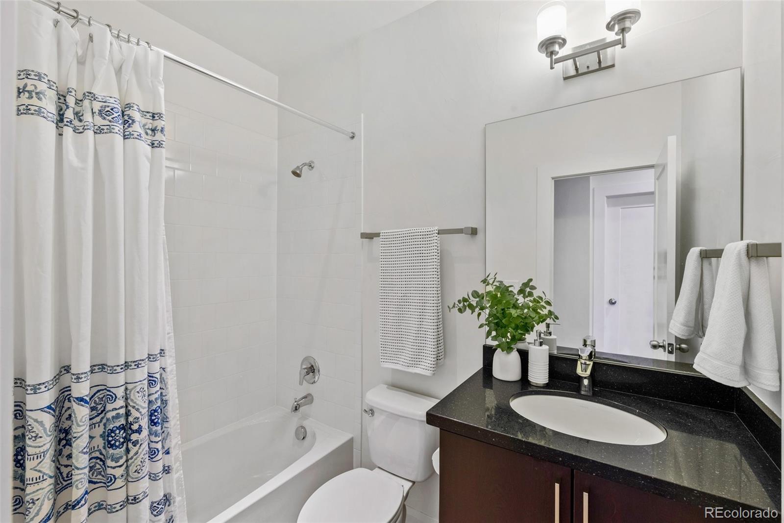 6731 Raritan Drive Denver, CO 80221 - Photo 28 of 40 a bathroom with a granite countertop sink a toilet and a mirror