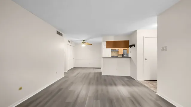 a view of a room with wooden floor and a kitchen space