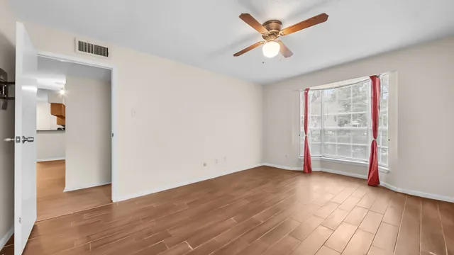 a view of a room with wooden floor and a ceiling fan