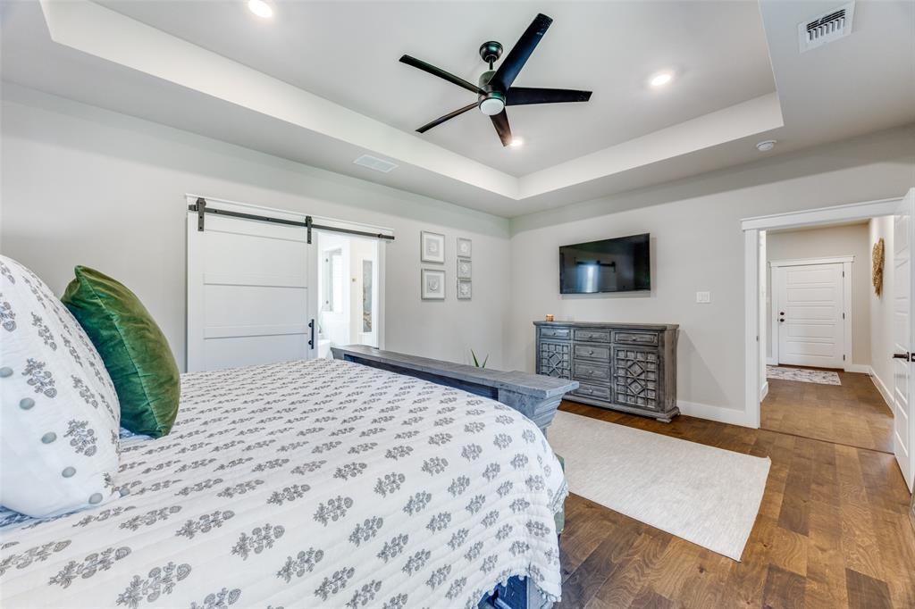 9425 Dripping Springs Road Denison, TX 75021 - Photo 16 of 39 a spacious bedroom with a large bed a flat tv screen and a fireplace