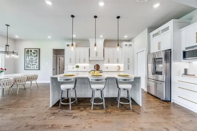 a kitchen with stainless steel appliances kitchen island granite countertop a table chairs and a refrigerator