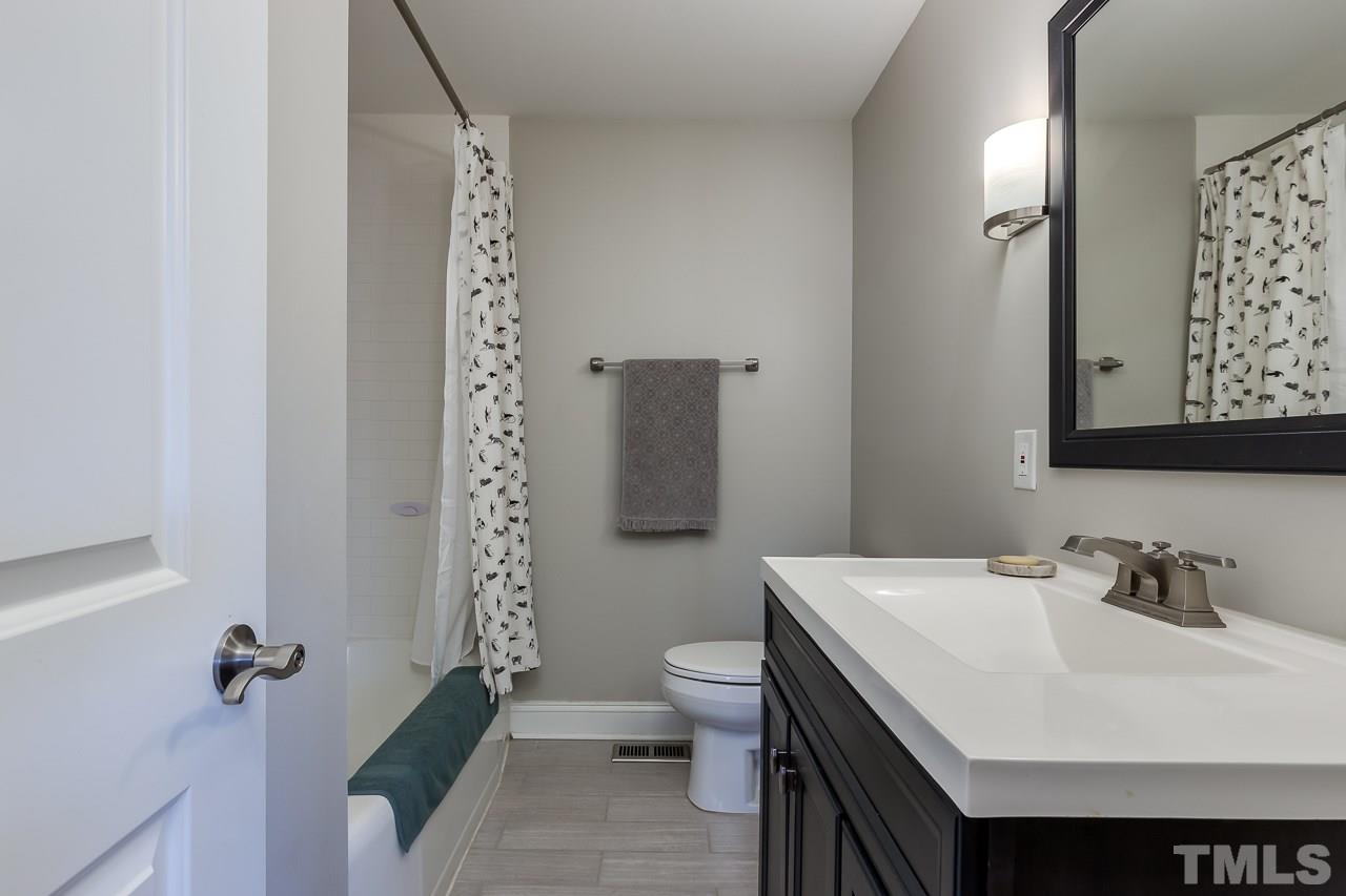 2411 Boswell Road Raleigh, NC 27610 - Photo 22 of 26 a bathroom with a sink a toilet and shower curtain