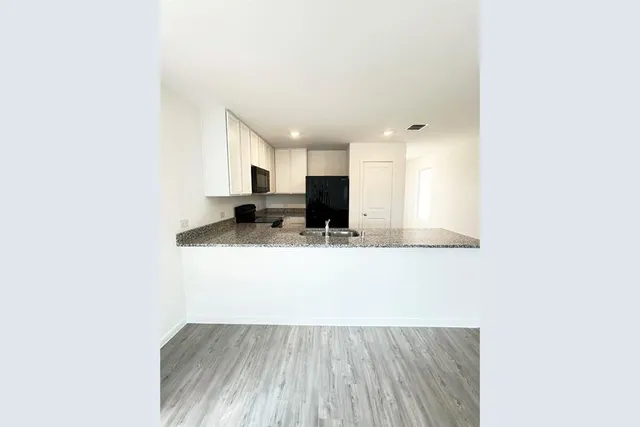 a view of kitchen with granite countertop cabinets and refrigerator