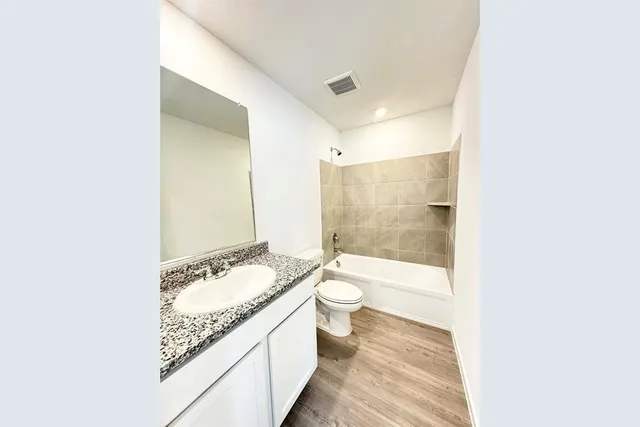 a bathroom with a granite countertop sink a toilet a mirror and bathtub