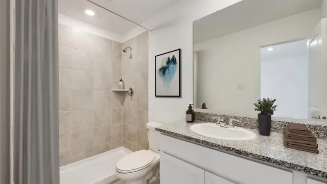 a bathroom with a granite countertop sink a toilet a mirror a vanity and shower