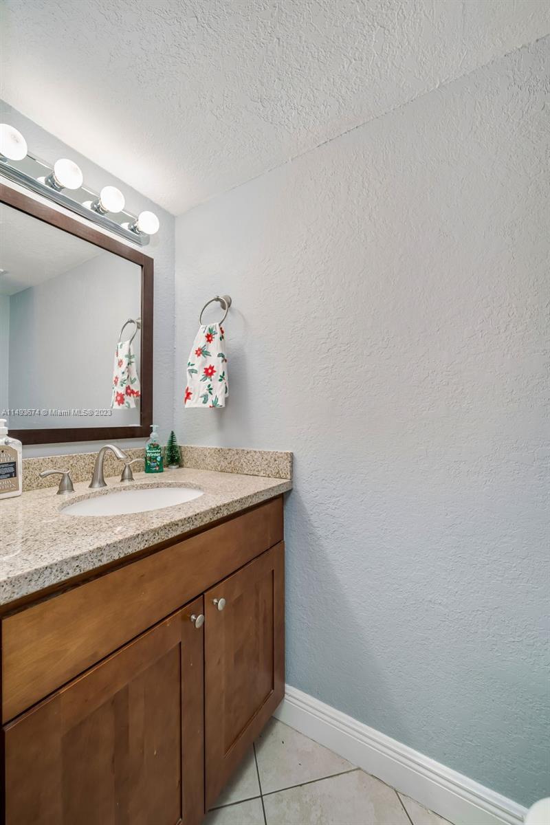 256 Southwest 6th Street, Unit 6 Boca Raton, FL 33432 - Photo 21 of 39 a bathroom with a granite countertop sink and a mirror