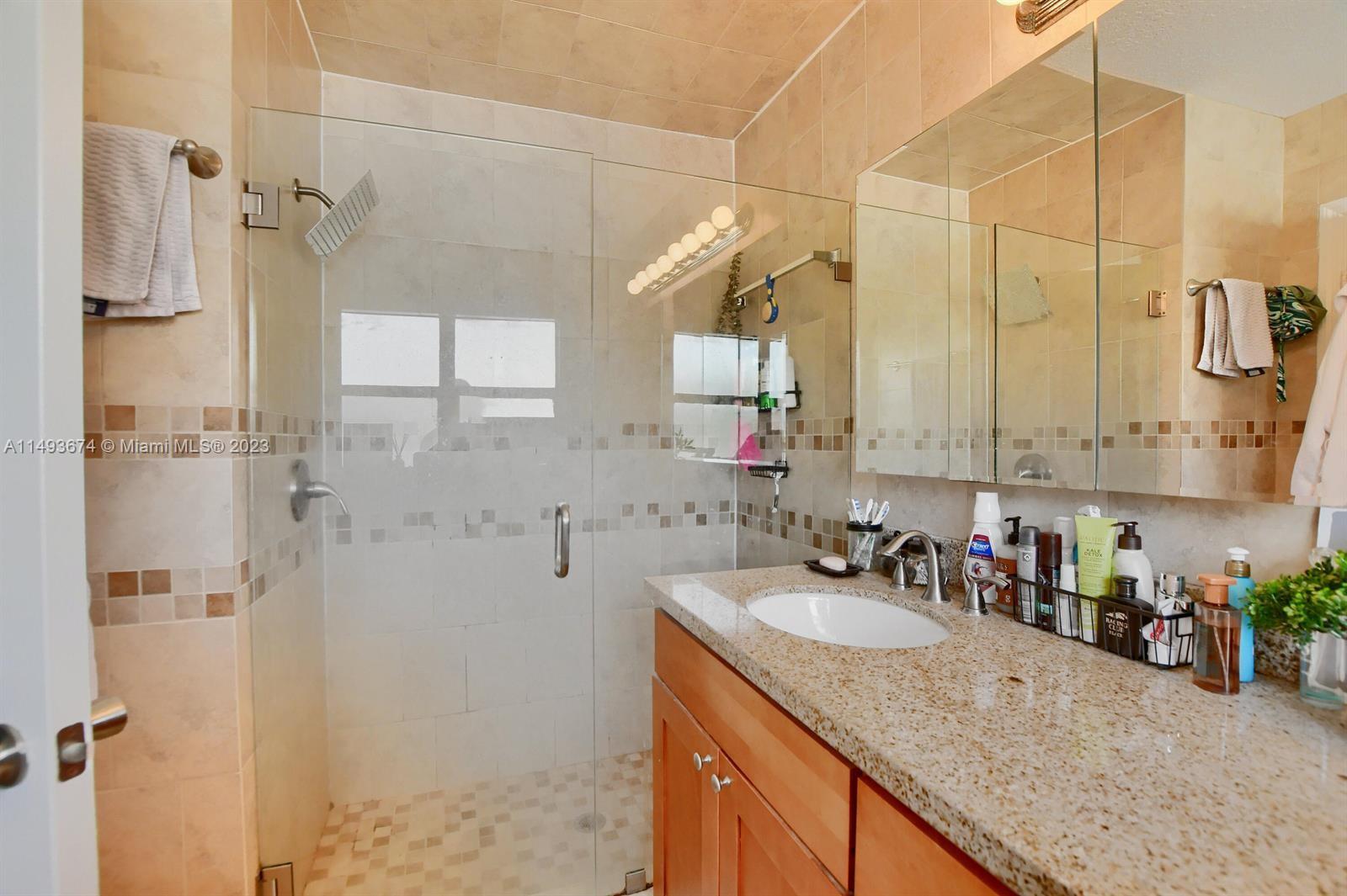 256 Southwest 6th Street, Unit 6 Boca Raton, FL 33432 - Photo 27 of 39 a bathroom with a granite countertop sink a mirror and shower