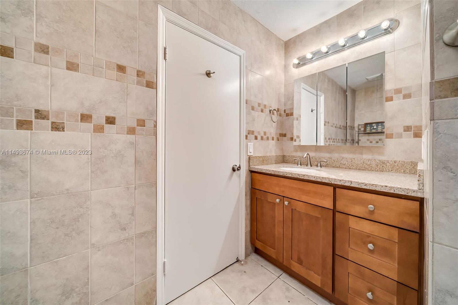 256 Southwest 6th Street, Unit 6 Boca Raton, FL 33432 - Photo 35 of 39 a bathroom with a granite countertop sink mirror and double