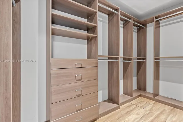 a view of an empty room with wooden floor and closet