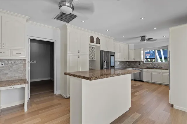 a kitchen with stainless steel appliances kitchen island granite countertop a refrigerator and a stove top oven