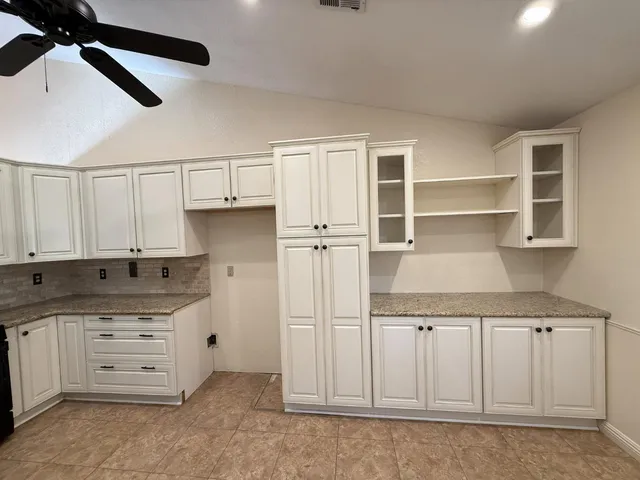 a kitchen with granite countertop a white stove top oven and cabinets