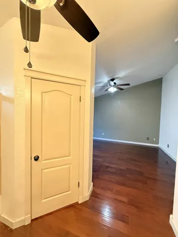 a view of empty room with wooden floor and fan