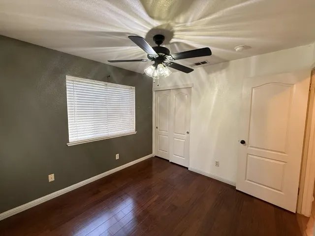 an empty room with wooden floor and ceiling fan