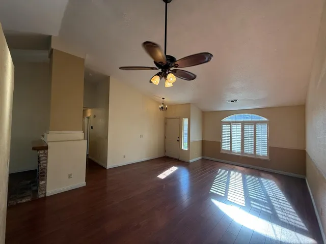 a view of an empty room with a window and wooden floor