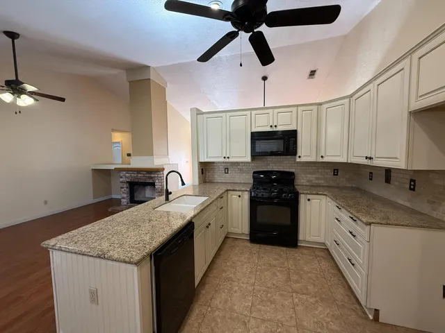 a kitchen with granite countertop a sink stainless steel appliances and white cabinets
