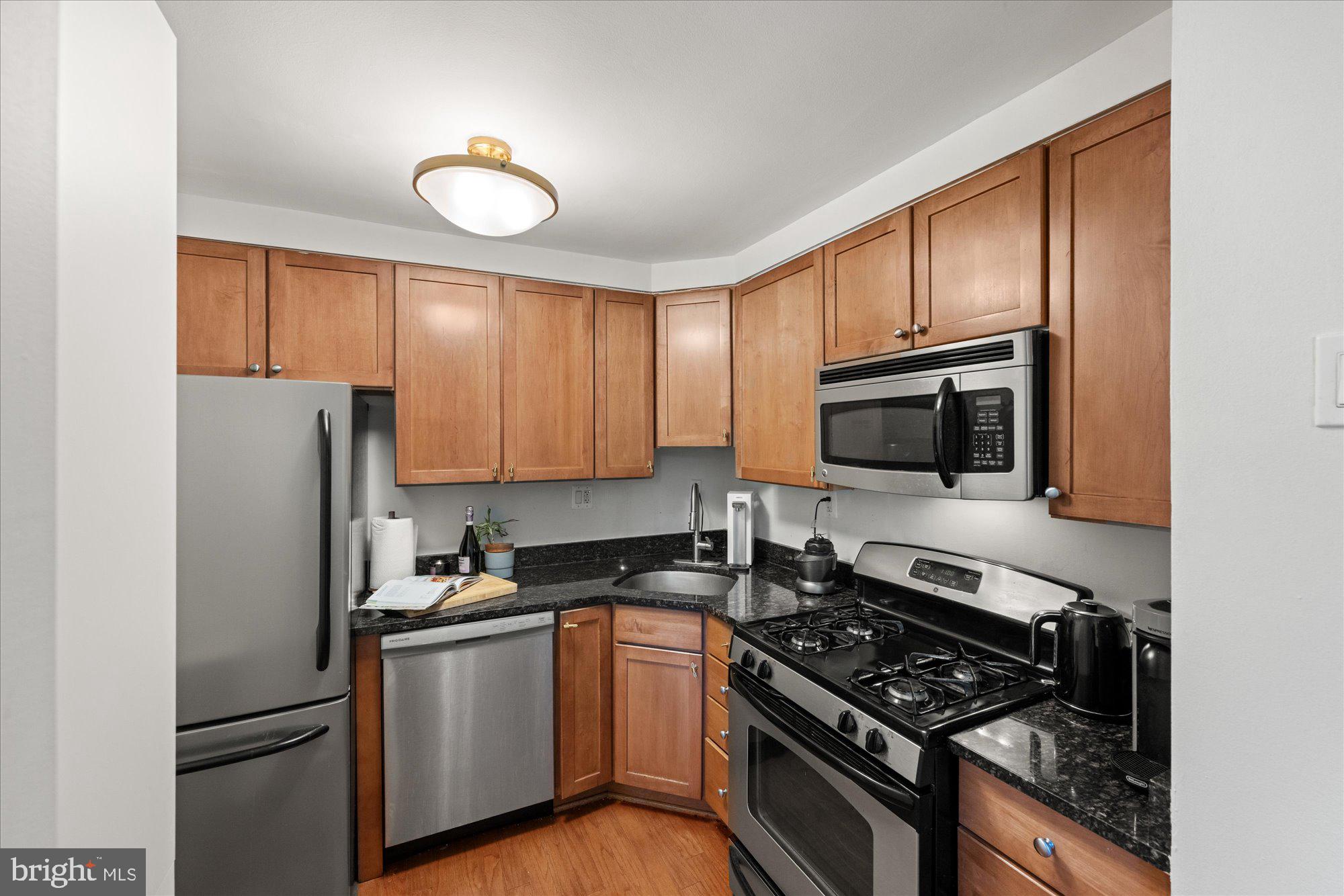 4840 MacArthur Boulevard Northwest, Unit 301 Washington, DC 20007 - Photo 12 of 24 a kitchen with stainless steel appliances granite countertop a refrigerator stove and microwave