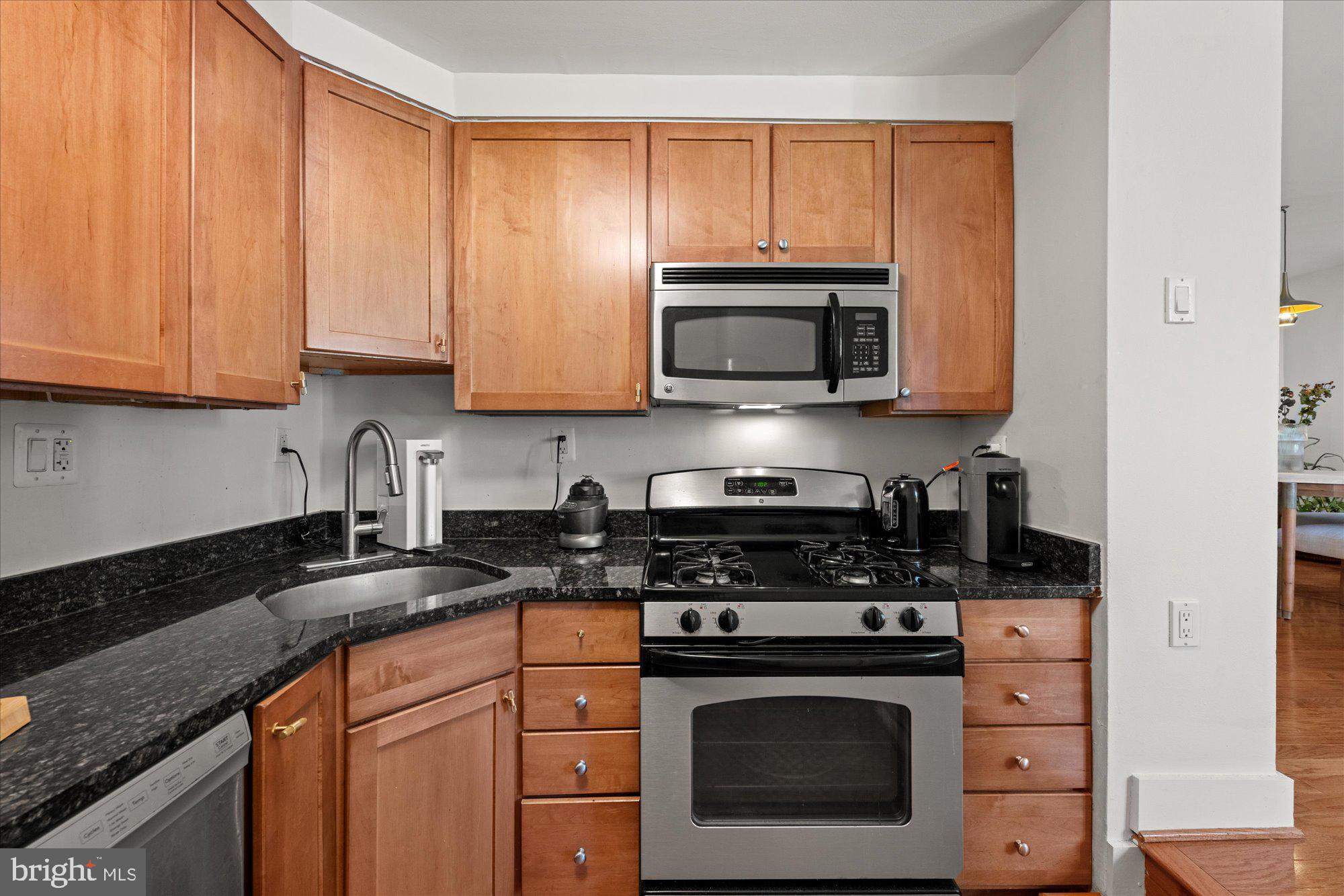 4840 MacArthur Boulevard Northwest, Unit 301 Washington, DC 20007 - Photo 14 of 24 a kitchen with granite countertop white cabinets stainless steel appliances and a sink