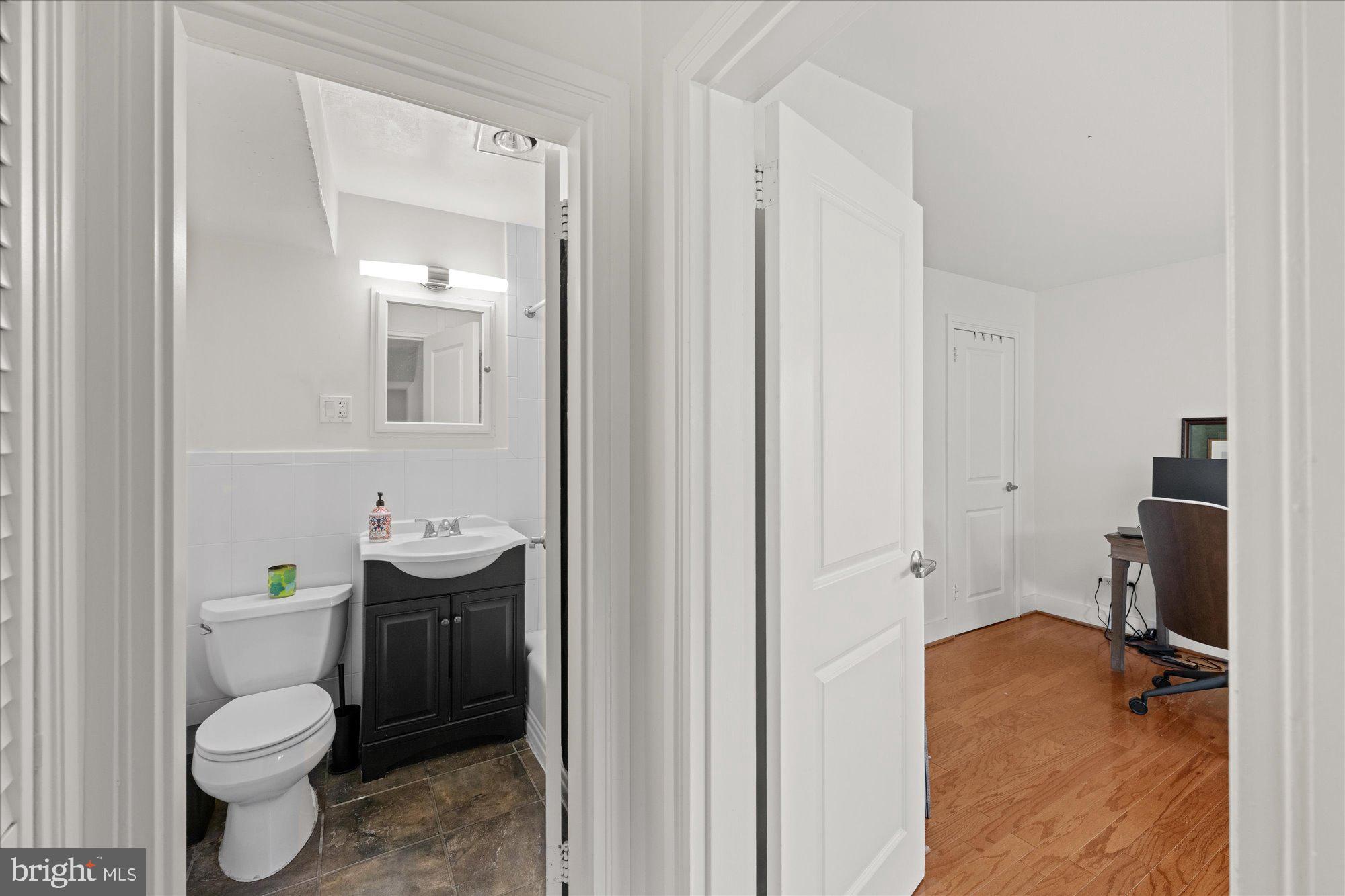 4840 MacArthur Boulevard Northwest, Unit 301 Washington, DC 20007 - Photo 18 of 24 a bathroom with a granite countertop toilet a sink and a mirror