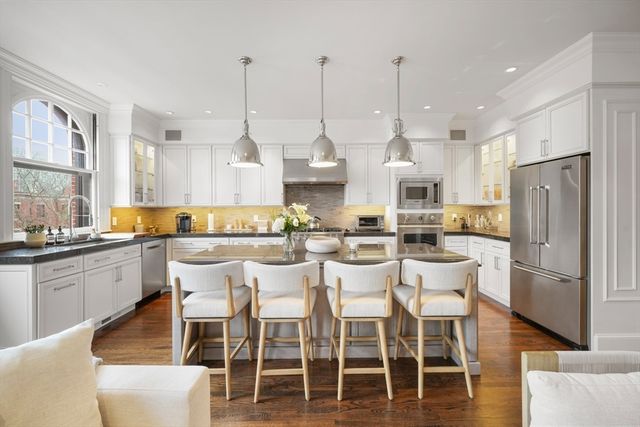 a kitchen with stainless steel appliances kitchen island granite countertop a dining table chairs and white cabinets