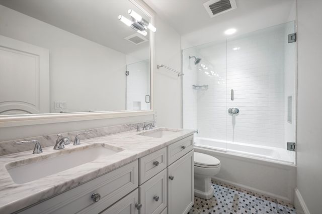 a bathroom with a granite countertop sink a toilet a tub and shower