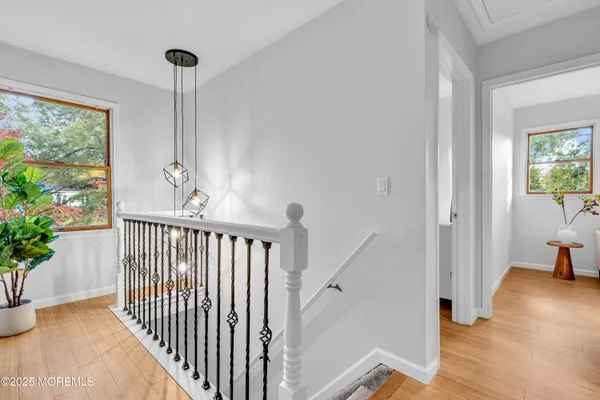a view of a hallway to a livingroom with furniture wooden floor windows and stairs