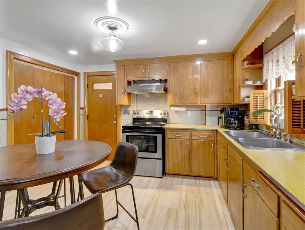 222 Walnut Street Saugus, MA 01906 - Photo 16 of 42 a kitchen with stainless steel appliances granite countertop a stove top oven a sink a dining table and chairs