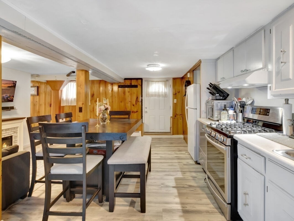 222 Walnut Street Saugus, MA 01906 - Photo 21 of 42 a kitchen with stainless steel appliances granite countertop a stove top oven a refrigerator a stove and a dining table with wooden floor
