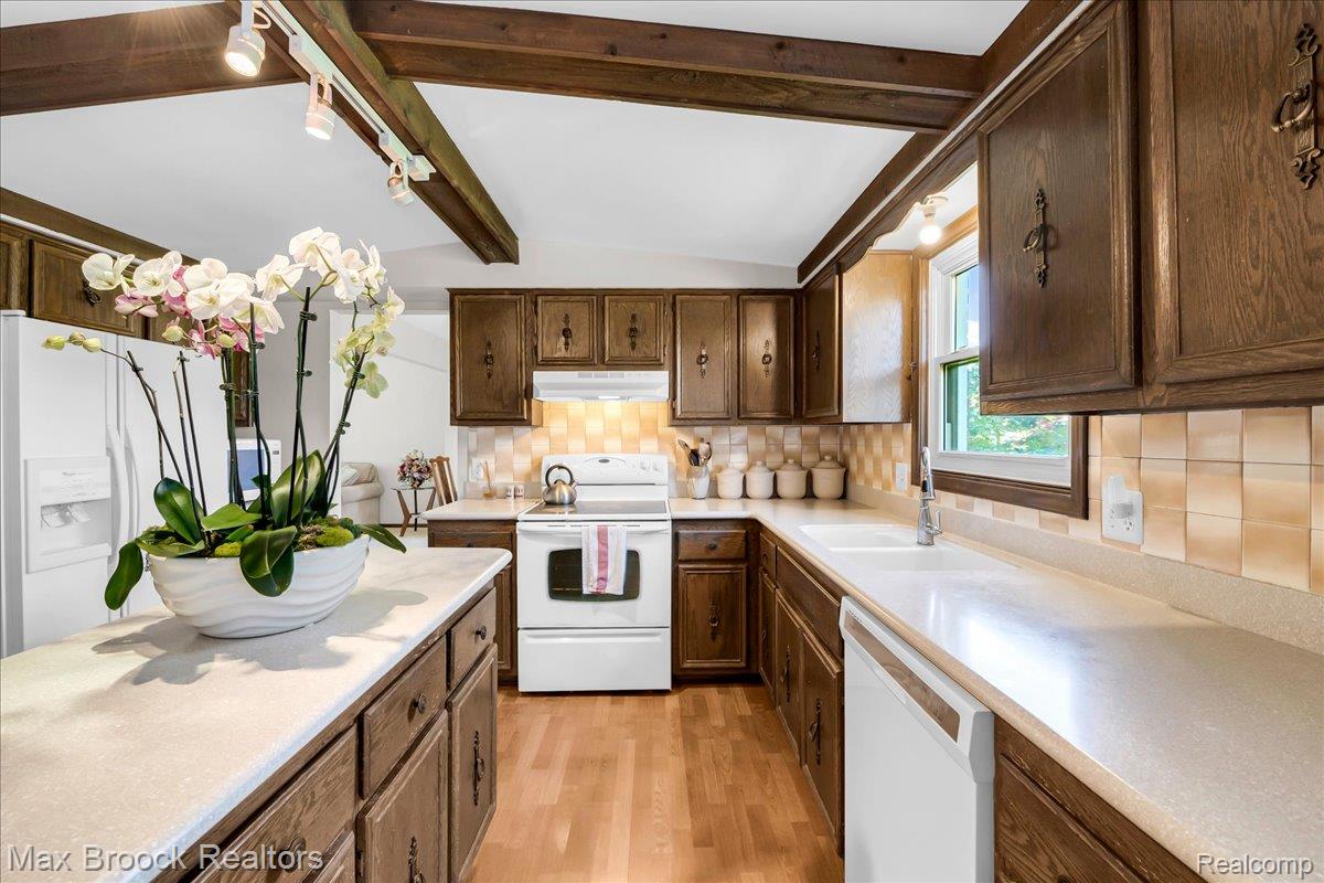 217 Stonetree Circle Rochester, MI 48309 - Photo 14 of 44 Kitchen featuring rich wood cabinetry, white countertops, tile backsplash, wood-finish flooring, and exposed ceiling beams with track lighting