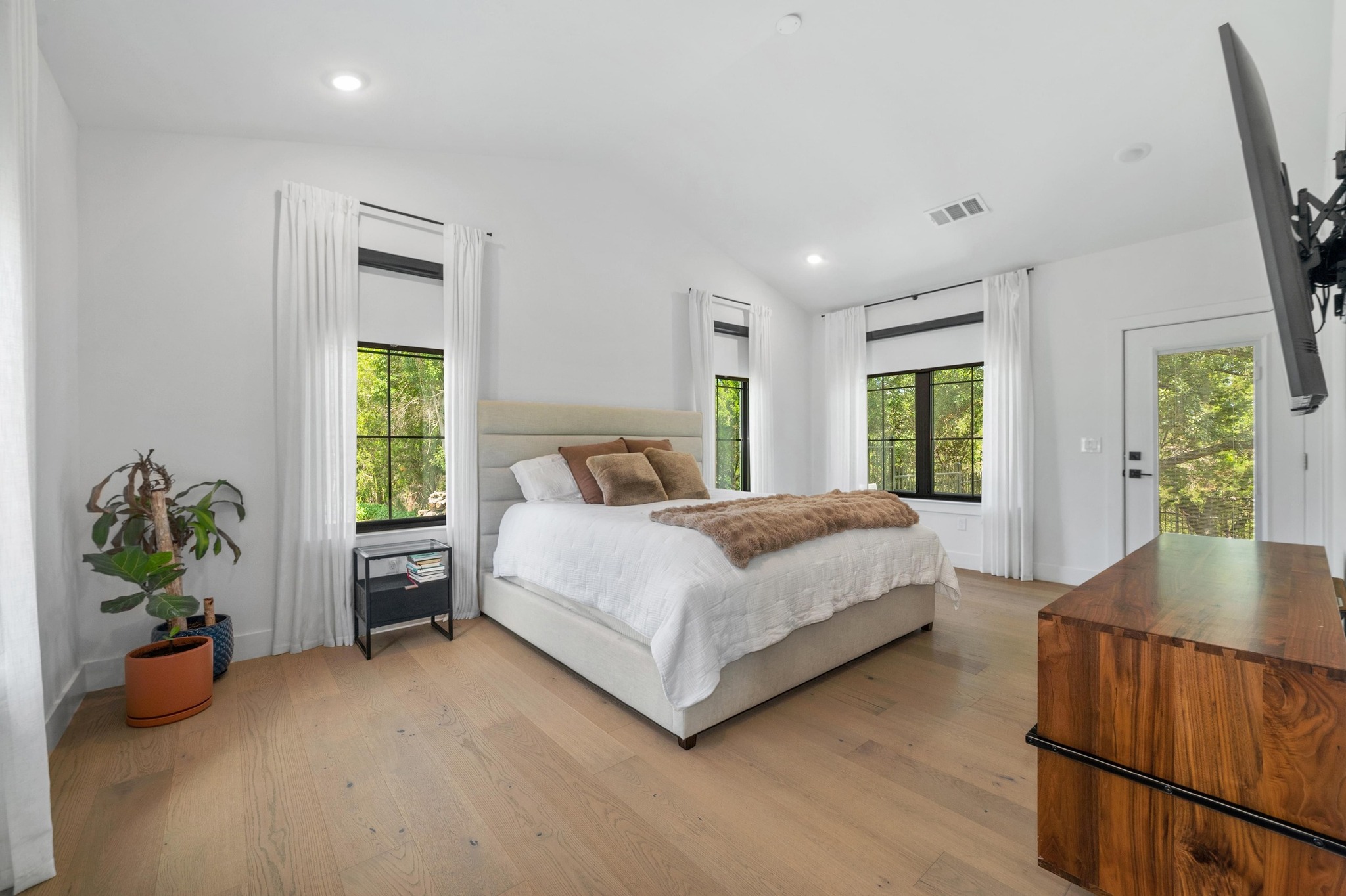 14302 Fallen Timber Drive Austin, TX 78734 - Photo 11 of 37 Well-lit room featuring light-toned hardwood flooring, recessed lighting, and multiple windows with white curtains