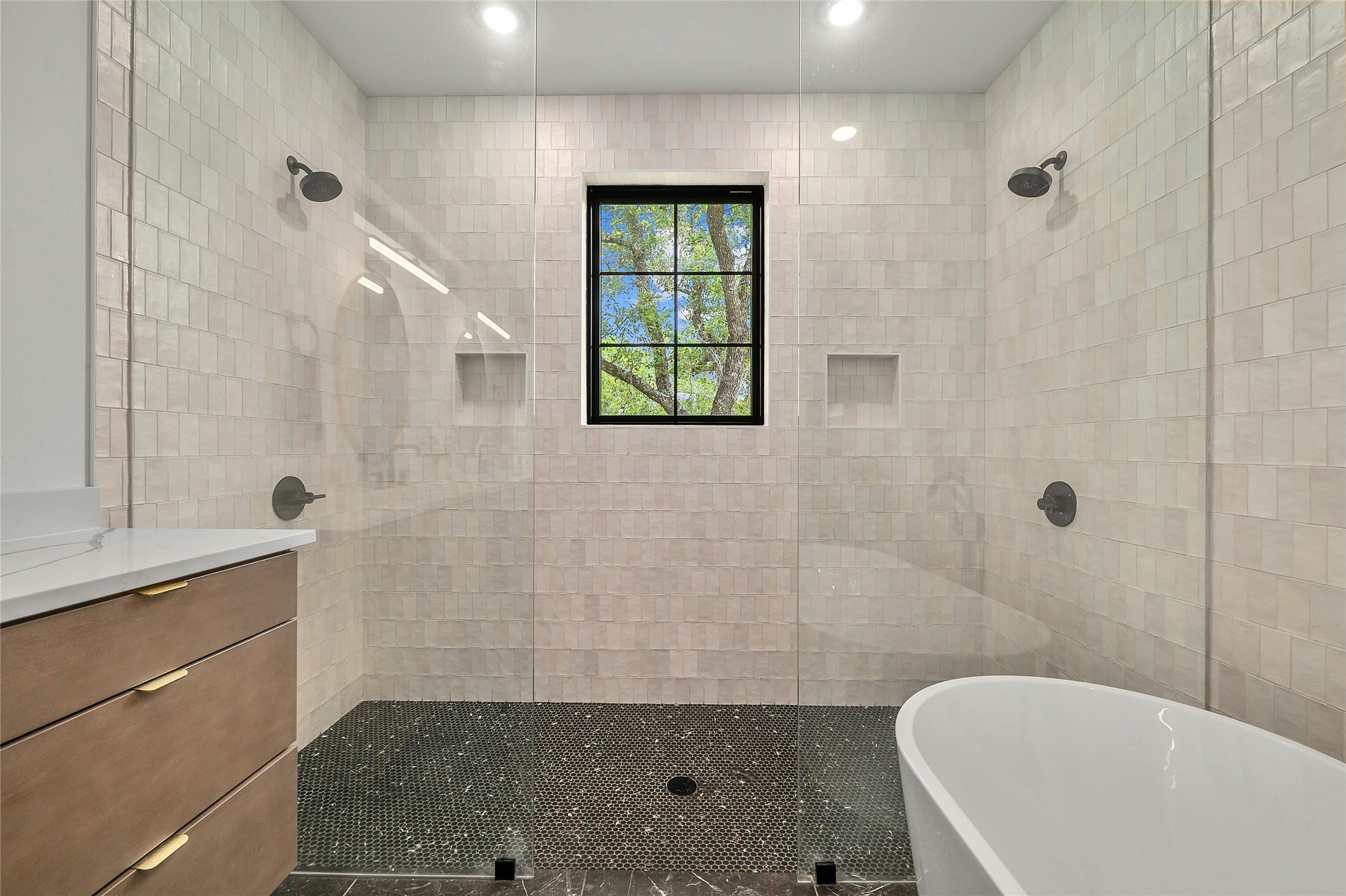 14302 Fallen Timber Drive Austin, TX 78734 - Photo 14 of 37 The bathroom features a spacious walk-in shower with clear glass panels, light-colored tiled walls, and a dark mosaic tile floor