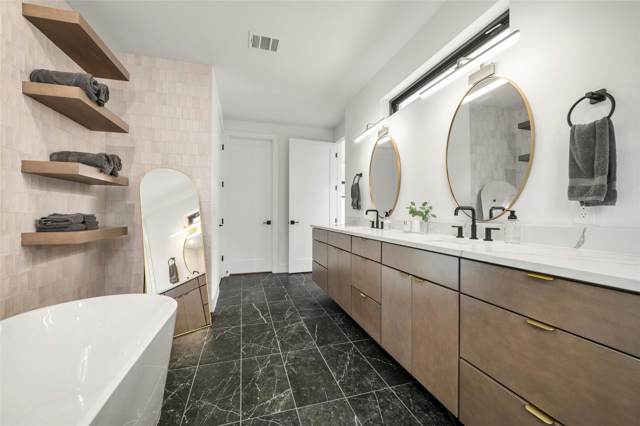 14302 Fallen Timber Drive Austin, TX 78734 - Photo 15 of 37 This bathroom features a freestanding tub, a lengthy double vanity with dual sinks, and black marble-style flooring
