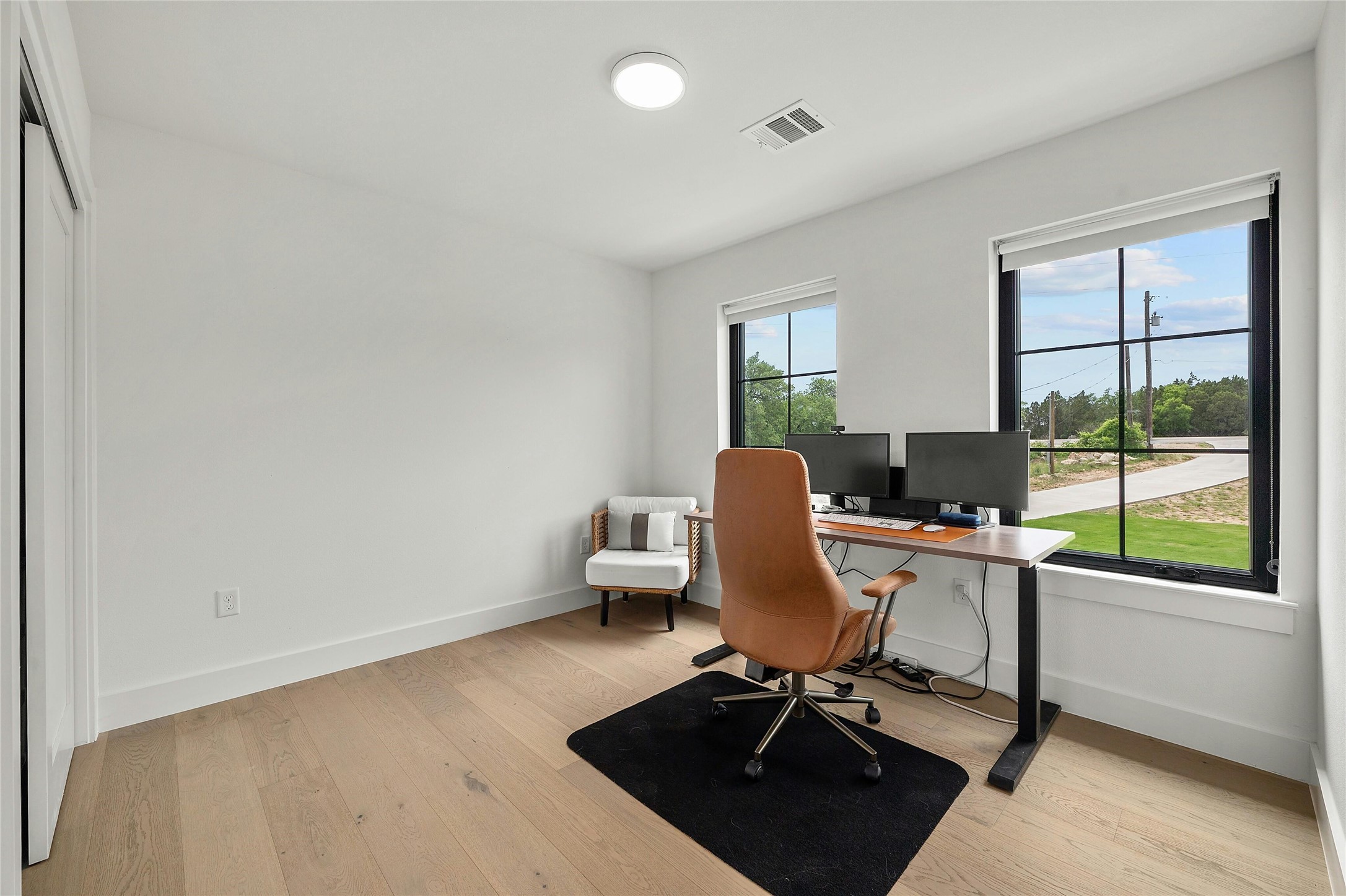 14302 Fallen Timber Drive Austin, TX 78734 - Photo 26 of 37 This bright room features light hardwood flooring and two windows with black frames, offering views of the outdoors