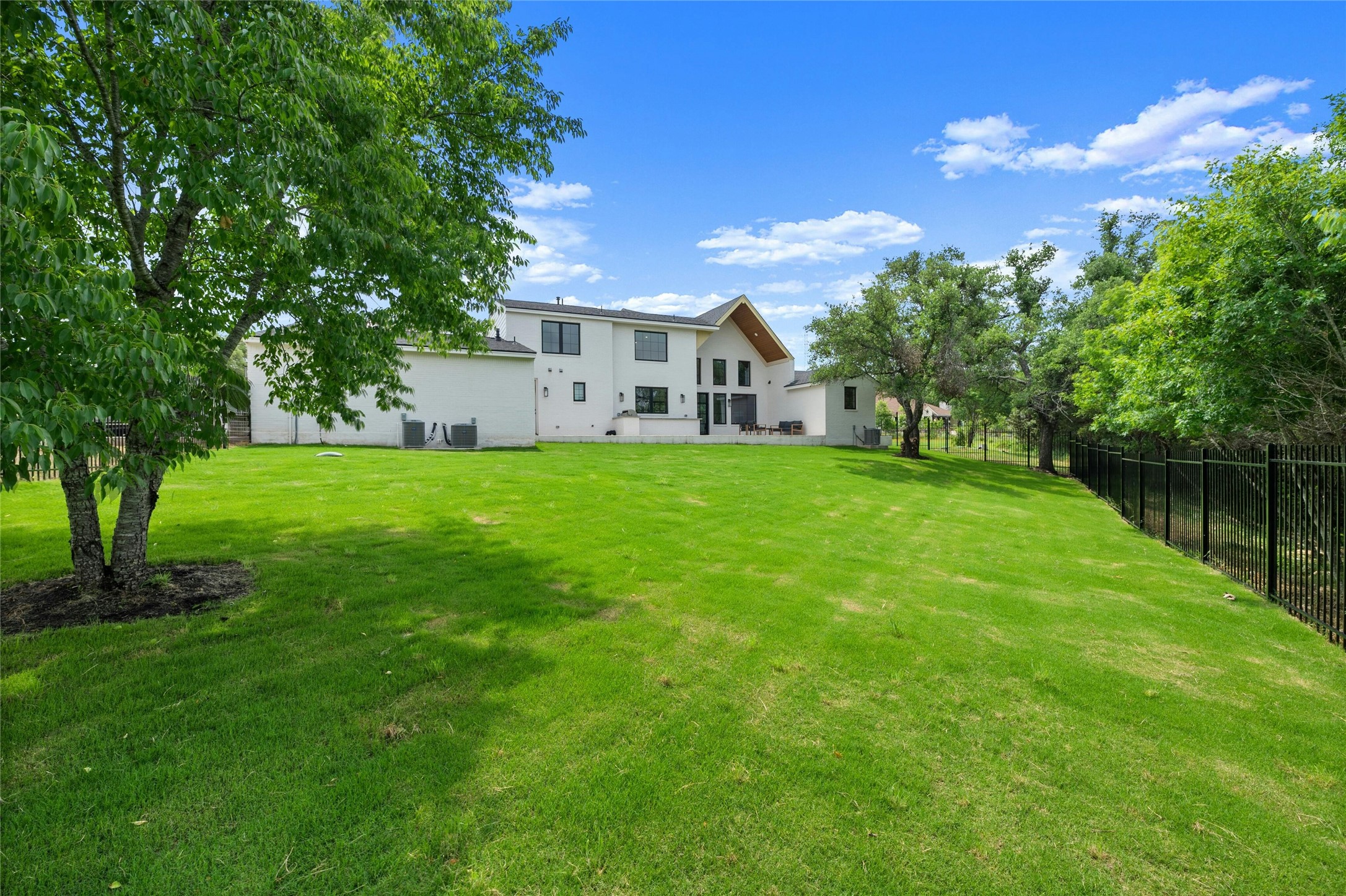14302 Fallen Timber Drive Austin, TX 78734 - Photo 30 of 37 The property features an extensive lawn with mature trees and a black metal fence bordering the lot