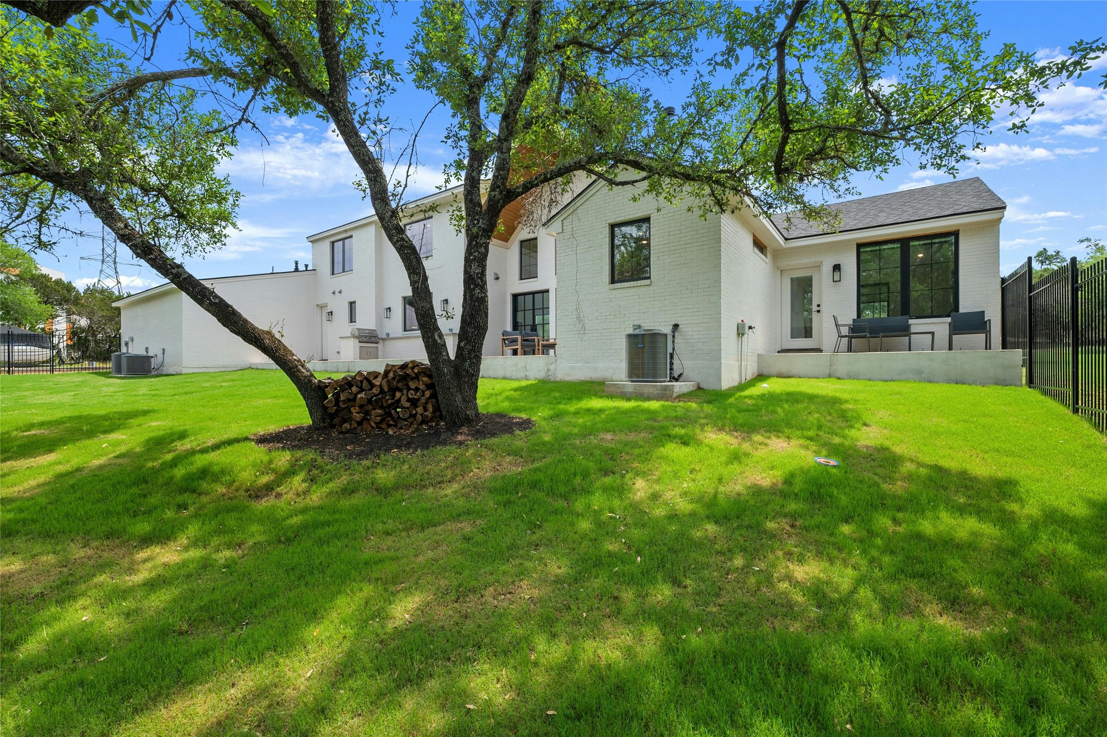 14302 Fallen Timber Drive Austin, TX 78734 - Photo 31 of 37 Expansive rear yard featuring a lush lawn, mature trees, and a white brick exterior