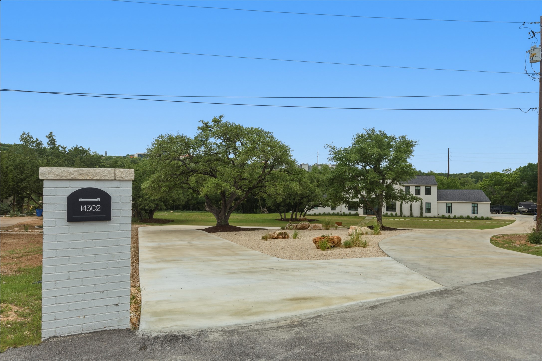 14302 Fallen Timber Drive Austin, TX 78734 - Photo 32 of 37 The property features a white brick mailbox pillar with a stone cap, a circle driveway, and mature trees